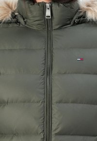 Zielona pikowana kurtka z wysokim kołnierzem, zamkiem błyskawicznym i ozdobą z sztucznego futra. Posiada małe logo na piersi oraz pikowaną fakturę.