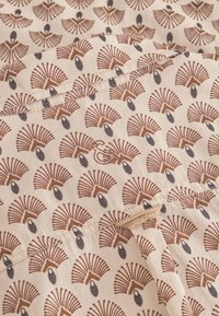 Tessuto leggero con un motivo ripetuto di forme a ventaglio marroni con accenti neri su uno sfondo beige, cucito con un filo abbinato.