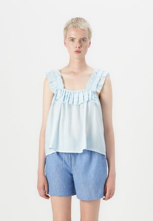 Lys blå rynket bluse med samlet halslinning og brede stropper, parret med blå og hvite stripete shorts. Myk stoff, løs passform.