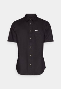 Chemise noire à manches courtes avec un col boutonné, une poche poitrine et une étiquette ; fabriquée dans un tissu lisse et léger avec une coupe ajustée.