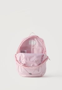 Ανοιχτό ροζ σακίδιο πλάτης που δείχνει το εσωτερικό θήκη και κενή ετικέτα ονόματος σε απλό λευκό φόντο.