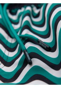 Tissu à motif ondulé vert, noir et blanc avec cordons turquoise dotés d'embouts en plastique noir marqués "DIDIBRE."