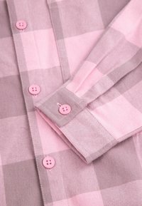 Różowa i szara koszula w kratę z miękkiego materiału, z przodem na guziki oraz różowymi guzikami na mankietach i listwie. Wzór zawiera dużą kratkę.