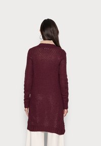 Burgundský pletený cardigan s volným střihem, dlouhými rukávy, žebrovanými manžetami a texturovaným vzorem, sahající pod boky.