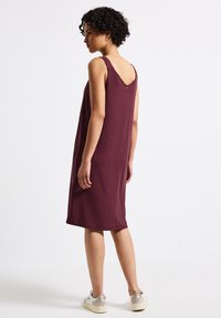 Ribbed, hihaton mekko syvässä burgundinvärisessä, puolipitkäss�ä mitassa, jossa on V-mallinen selkäosa. Yhdistetty rentoihin lenkkareihin, joissa on hienovarainen brändäys takana.