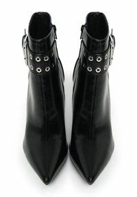 Botas de tobillo de cuero negro con punteras puntiagudas, que presentan una correa decorativa con hebilla y ojales de metal alrededor del tobillo. Textura suave.