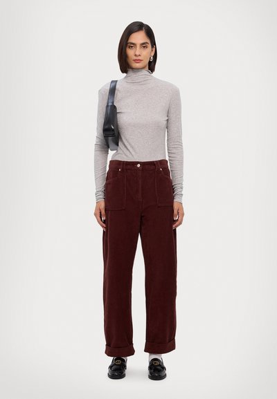 Gray turtleneck sweater, burgundy corduroy wide-leg pants with side pockets, black handbag, and black loafers on a neutral background.