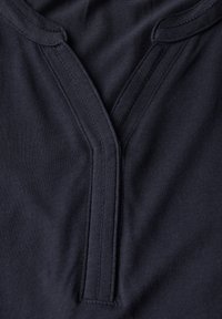 Tissu marine avec une texture lisse, présentant un design classique en V et des coutures détaillées le long de l'encolure et de la patte de boutonnage.
