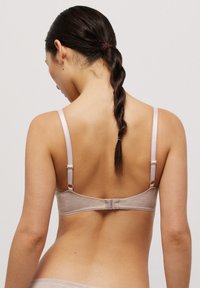 Sujetador marrón claro con tirantes ajustables de color rosa y cierre de gancho. Tejido suave y texturizado con un diseño sencillo y bordes con forma de concha.