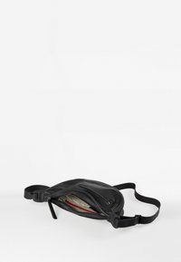 Borsa a tracolla in pelle nera con forma curva, tracolla regolabile e tasca esterna con zip. L'interno presenta una fodera a motivo con accenti rossi.