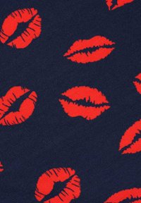 Πλεκτό ύφασμα σε ναυτικό μπλε χρώμα διακοσμημένο με κόκκινους τύπους φιλιών, με διάφορα μεγέθη και στυλ αποτυπωμάτων χειλιών σε όλη την επιφάνεια.