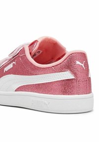 Baskets pailletées roses avec des accents blancs, dotées d'une sangle Velcro, d'un col rembourré et d'une surface texturée. Logo Puma sur le côté.
