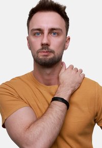 Bracciale nero intrecciato indossato al polso di una persona in una maglietta in tessuto giallo senape, che mette in risalto colori e materiali a contrasto.