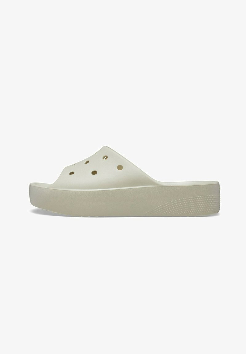 Tamanco slip-on de tom bege claro, feito de plástico macio, com orifícios de ventilação, sola grossa e fundo texturizado para garantir aderência.