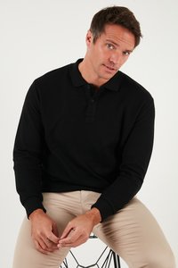 Melnas ribota garām piedurknēm polo krekls ar apkakli, ar trīs pogu aizdari un kontrastējošām aprocēm, apvienots ar iedobēm bežām biksēm.