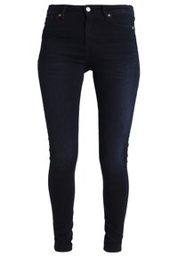 Mörkblå denim skinny jeans med en figurnära design, knappstängning och framfickor. Slät textur med minimala detaljer.