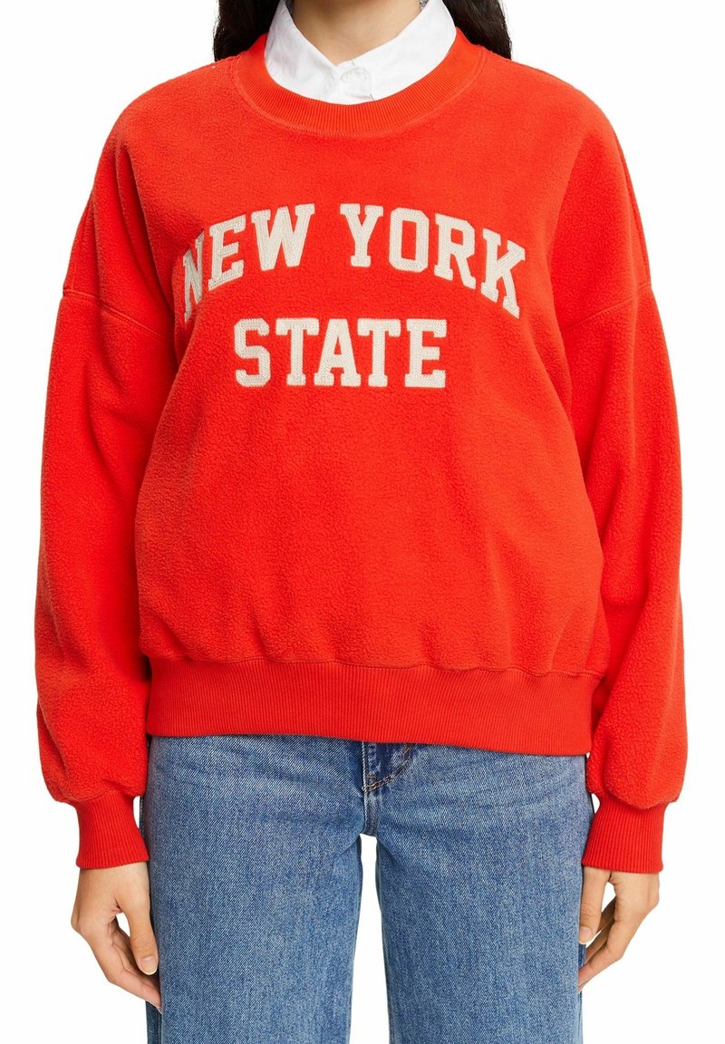 Sweat-shirt en polaire rouge avec « NEW YORK STATE » imprimé en crème. Comprend des poignets et un ourlet côtelés, une coupe décontractée et une texture douce.