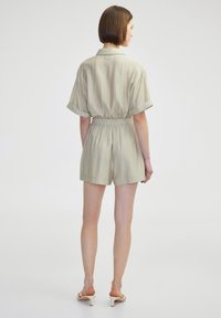 Romper vert clair à col avec manches courtes, taille élastique et tissu texturé. Design de short court avec une coupe décontractée.