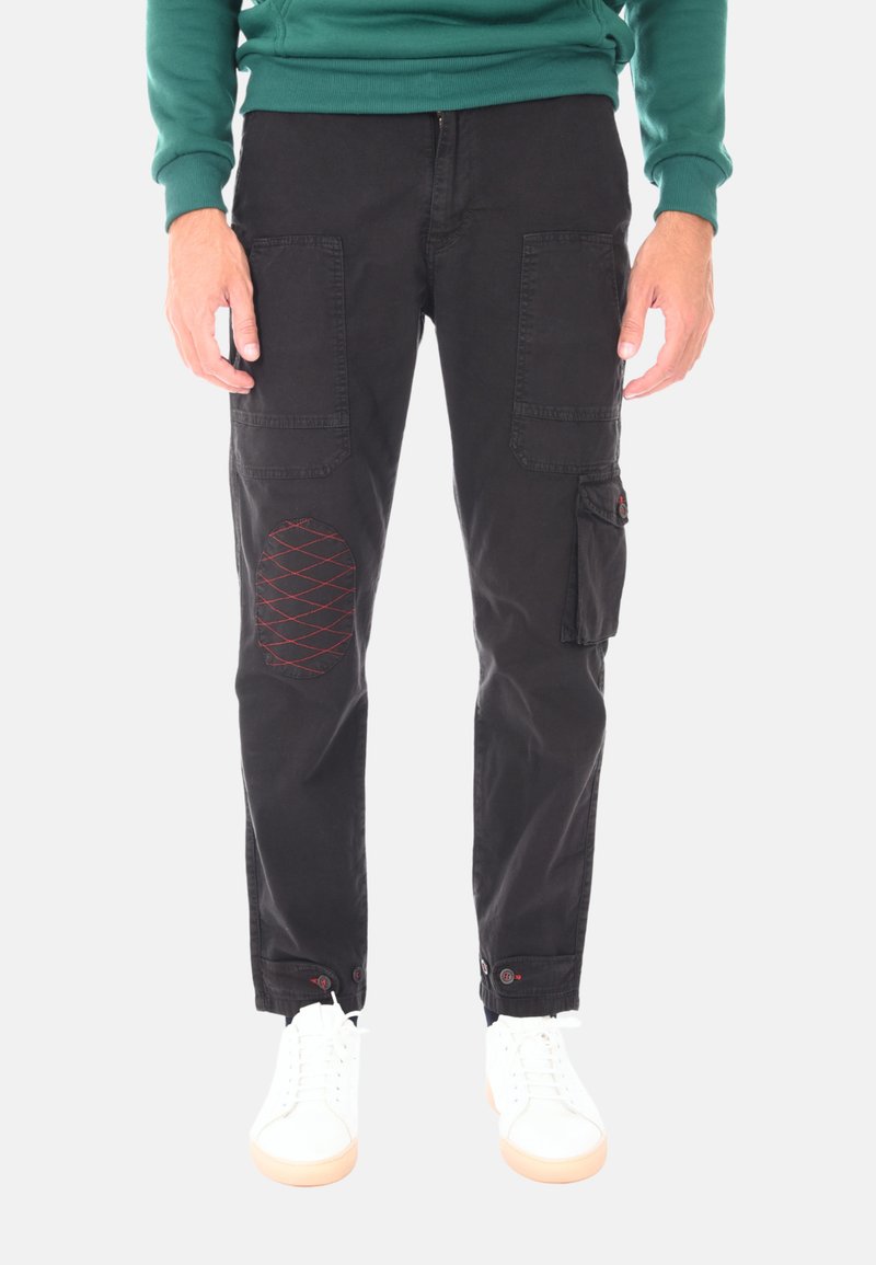 Pantaloni cargo neri in cotone, con ampie tasche laterali, una toppa rossa cucita sul ginocchio e dettagli con bottoni ai polsini.