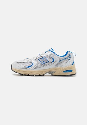 Biało-niebieski but do biegania New Balance 530 z beżową podeszwą i detalami z siateczkowej tkaniny, widoczny z boku na jednolitym tle.