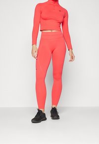 Completo per performance in corallo composto da un top corto a maniche lunghe e leggings aderenti, realizzati in tessuto elasticizzato con dettagli logo e cuciture piatte.