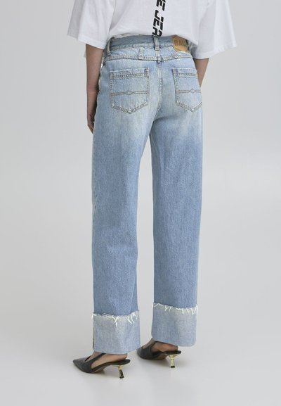 Helle blaue, hochgeschnittene Jeans mit lockerer Passform und fransigen Säumen. Fünf-Taschen-Design mit subtilen Verblassungen auf dem Stoff und Lederetikett auf der Rückseite.
