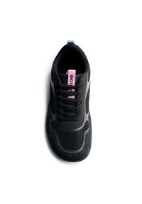 Zapatilla deportiva negra que presenta materiales de malla y ante, punta redonda, suela de goma texturizada, cordones y una etiqueta de marca rosa en la lengüeta.
