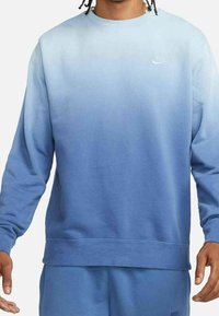 Modrý gradientový svetr vyrobený z měkké tkaniny. Dlouhé rukávy, kulatý výstřih, s jemným logem Nike na hrudi a uvolněný střih.