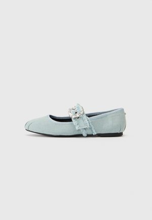 Zapato plano de tela azul claro con una correa deshilachada y hebilla plateada adornada, y suela negra sobre un fondo liso.