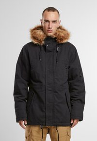 Fekete parkajacket szőrmebéléses kapucnival, húzózsinóros részletekkel, több zsebbel és elülső zipzárral. Texturált anyag, tartós kivitel.
