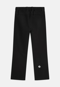 Svarta tights med resårmidja, rak bendesign och en liten vit logotyp på vänster nederben. Slät textur, inga mönster.