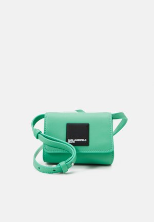 Groene faux leren crossbody tas met een flap, verstelbare band en een vierkant logo patch. Glad textuur en compacte rechthoekige vorm.