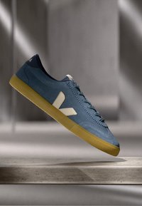 Adidași din piele albastră cu logo crem, superior texturat și talpă din cauciuc galben; dispun de șireturi rotunde și un design cu profil jos.