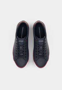 Zapatillas de marino con un acabado suave, detalles en rojo alrededor del collar y suelas de goma blanca. Presenta cordones planos y el logotipo en la lengüeta.