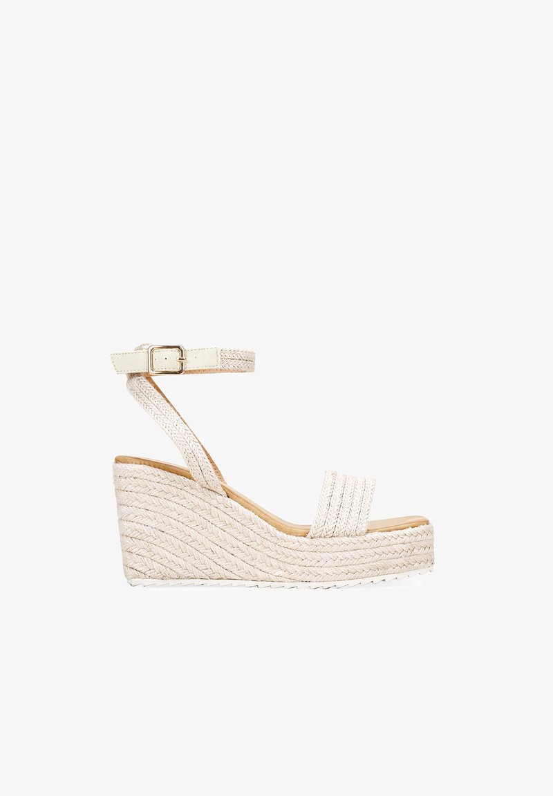 Wedge-Sandalen aus cremefarbenem, gewebtem Stoff mit einem Knöchelriemen und einer Schnalle, die ein strukturiertes, geflochtenes Design und einen Holzabsatz präsentieren.