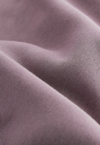 Tissu doux et texturé dans une couleur lavande douce, affichant des plis lisses et tombants en douceur ainsi qu'un motif de tissage uniforme et fin.
