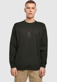 Tricou negru cu mâneci lungi, având un design cu o mână albă și o inimă roșie. Fabricat dintr-un material moale, are guler rotund și un croi lejer.