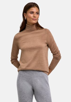 Brauner Rollkragenpullover aus weichem Material mit langen Ärmeln; getragen mit hellgrauen Hosen, die eine lässige Passform und eine glatte Textur aufweisen.