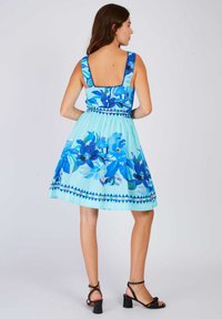 Blaues Blumenkleid mit quadratischem Rückenteil, breiten Trägern und einem ausgestellten Rock. Es hat ein Blumenmuster und dekorative Verzierungen an der Taille.