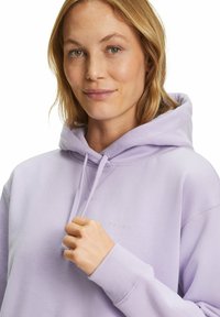 Lavender hoodie met een trekkoord capuchon en geribbelde manchetten. Zachte textuur met een subtiele logodetail op de borst.