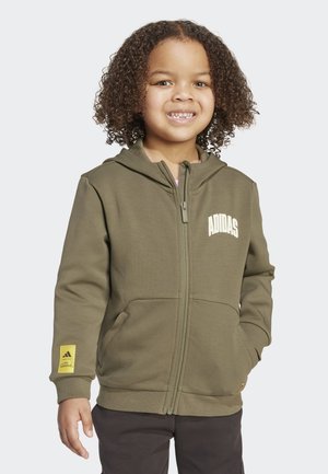 Sudadera con cremallera en color verde oliva, con bolsillos frontales, puños acanalados y un parche de logo amarillo en la manga. Tejido suave, diseño informal.
