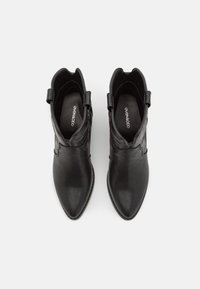 Černé kotníkové boty z hladké kůže, s špičatou špičkou, dekorativním prošíváním a poutky na bocích.