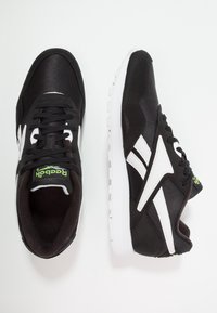Paire de baskets Reebok noires avec logo et semelles blanches, présentées vues de dessus et de côté sur un fond blanc.