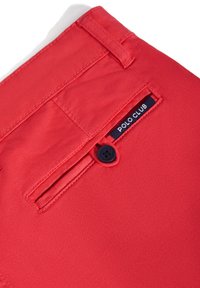 Röda tygshorts med en stilren design, en enda bakficka med en marinblå etikett som läser "POLO CLUB," och en svart knappdetalj.