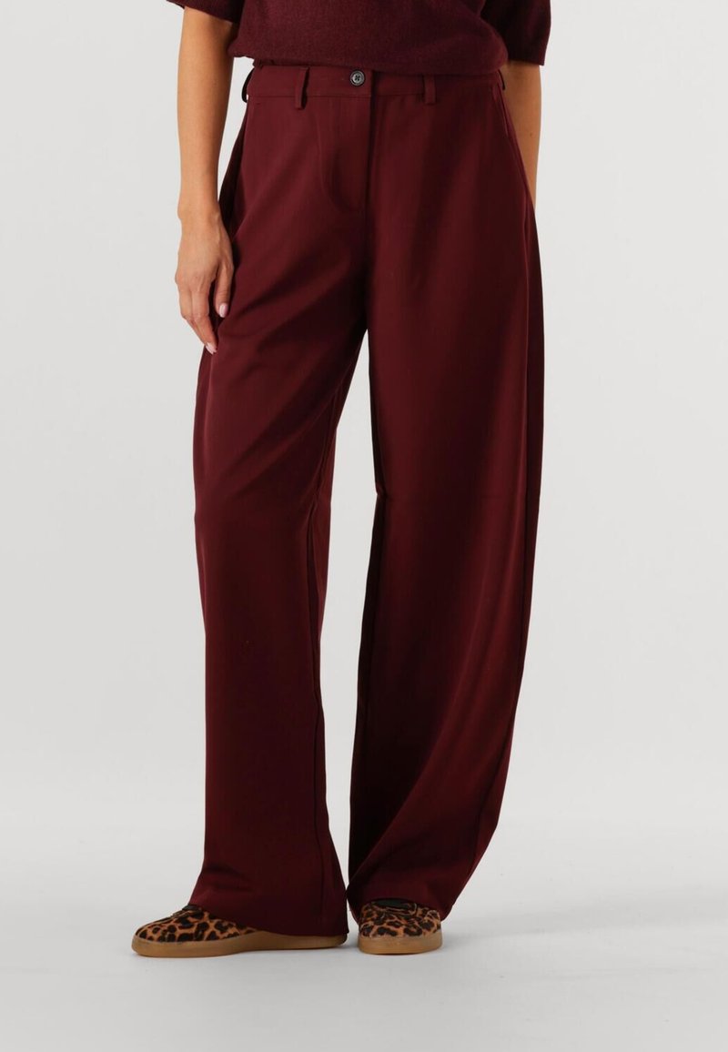 Bordeaux brede broek met een gladde textuur, voorzien van een sluiting met vorenknopen en twee zijzakken, gecombineerd met instappers met een luipaardprint.