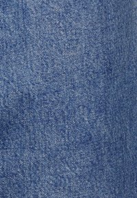 Denim-kangas keskisinisä sävyssä, jossa on kevyesti teksturoitu pinta, klassinen kudontakuvio ja hienovaraiset värivaihtelut.