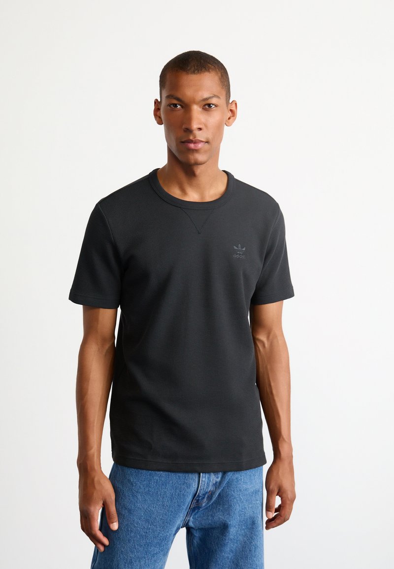 Must ülekaelusärk tekstuuriga musta värvi, ümar kaelus ja väike reljeefne logo vasakul rinnal. Koos siniste denimist teksadega.