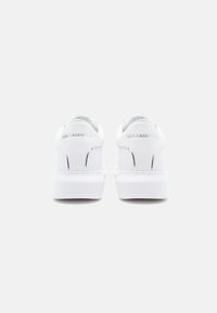 White sneakers with a smooth leather finish, thick sole, rounded edges, and embossed "KARL LAGERFELD" branding on the heel.