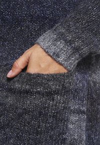 Gebreide trui in donkerblauwe en grijze tinten, met een textuurpatroon, brede mouwen en een voorkantzak met een zichtbare hand.