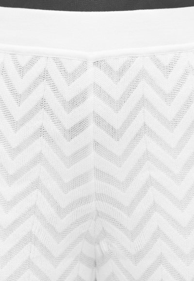 Κοντινή λήψη λευκού πλεκτού υφάσματος με σχέδιο σχημάτων βέλους και ολόκληρη ζώνη μέσης στην κορυφή.